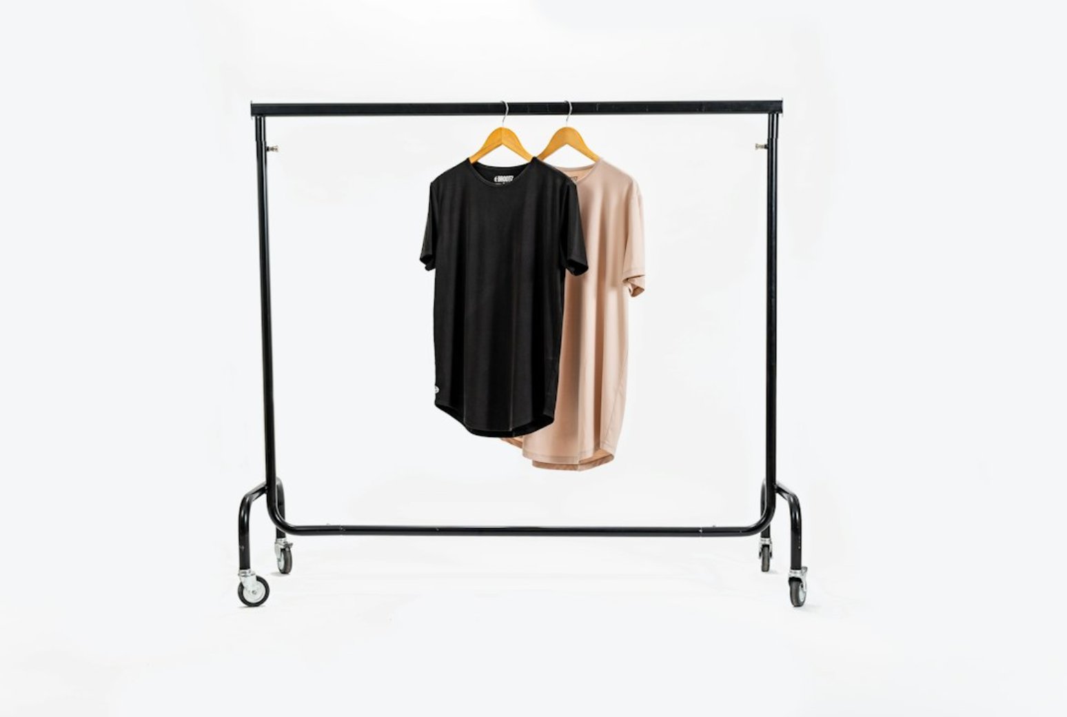 Two t-shirts, one black and one blush, hanging on a clothing rail.