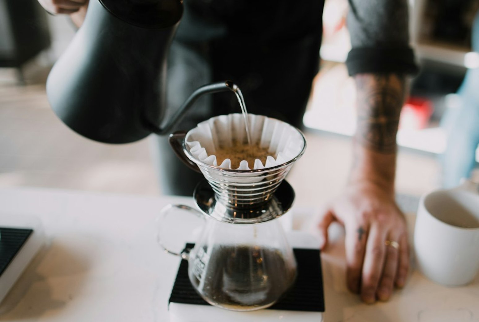 Pour-over coffee dripping through a paper filter into a glass carafe.
